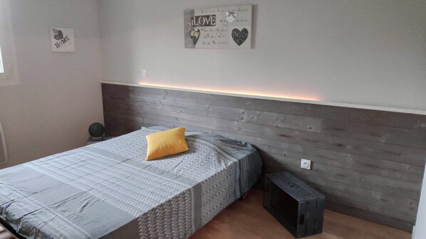 Ein Schlafzimmer mit einem Bett, einem Kopfteil, einem kleinen runden Tisch und einer Wanddekoration.