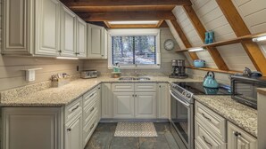 A kitchen with white cabinets, granite countertops, a window with blinds, a stove, and a microwave. - Rae of Sunshine by Innsbrook Vacations! (Innsbrook)