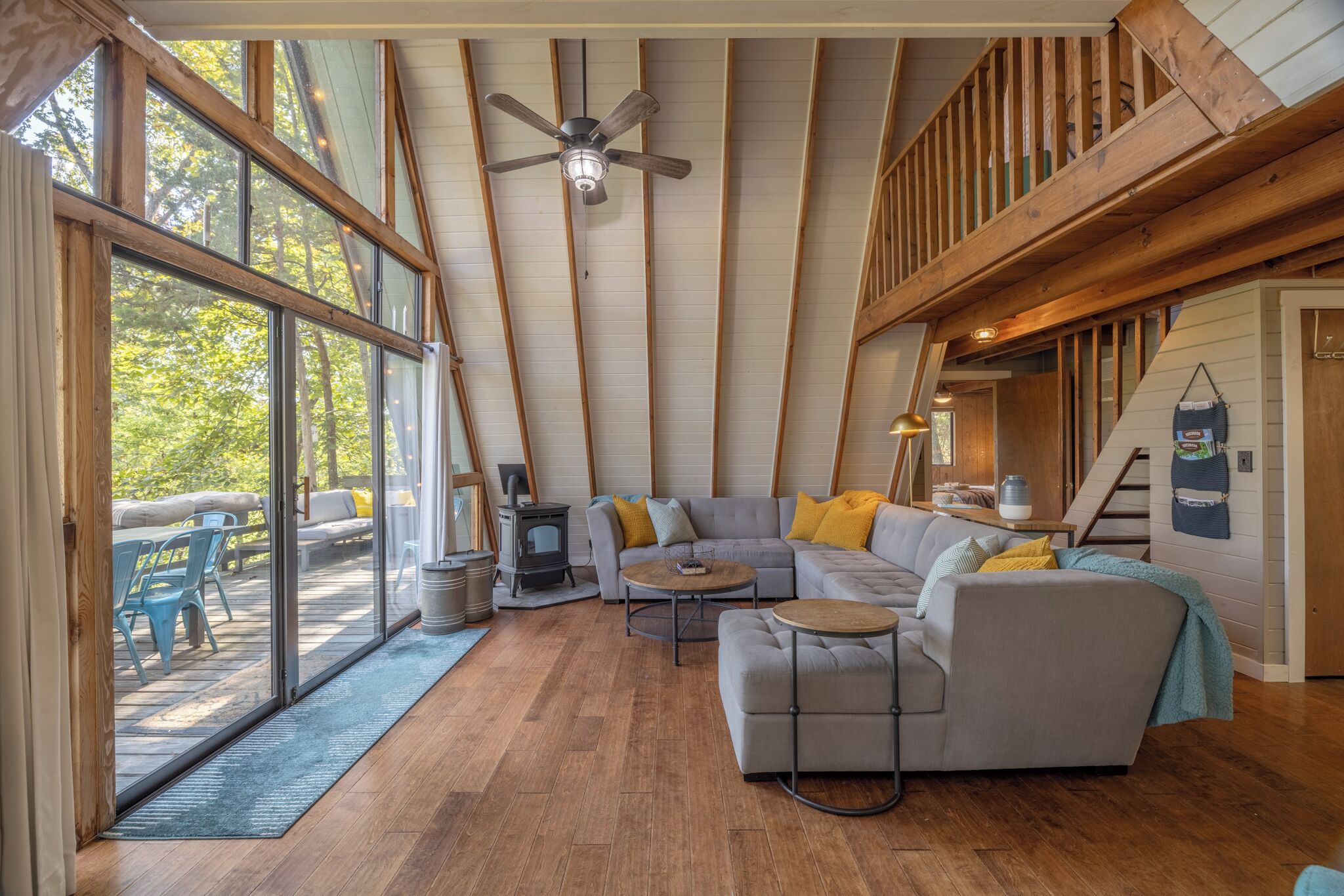 A spacious loft with a large sliding glass door leading to an outdoor area, a cozy seating area with a fireplace, and a wooden ceiling with exposed beams.