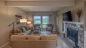 Un salon comprenant un canapé, deux fauteuils, une table basse, une cheminée et un téléviseur.