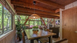 A wooden dining area with a table and chairs, a hanging light fixture, and a television in the background. - Snug Harbor by Innsbrook Vacations! (Innsbrook)