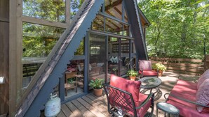 A wooden deck with a glass enclosure, red seating, and potted plants. - Snug Harbor by Innsbrook Vacations! (Innsbrook)