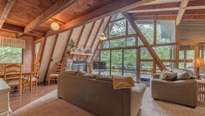 Una sala de estar acogedora con un sofá grande, sillas de madera y una chimenea.