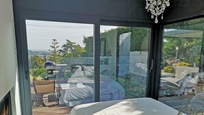 A bedroom with a large sliding glass door leading to a balcony with a view of the outdoors.