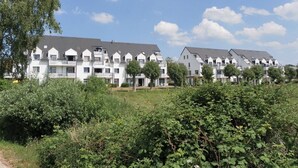 A row of modern, multi-story residential buildings with balconies, surrounded by greenery. - Haffblick Whg. Ha18, Deutschland (Ostseebad Boltenhagen)