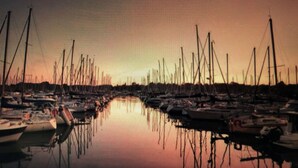 A marina with boats docked along the water, a bridge crossing the water, and a sunset sky. - House (53m2) for vacations by the sea (La Forêt-Fouesnant)