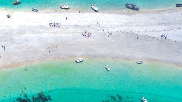 An aerial view of a beach with several boats anchored near the shore and people scattered across the sand. - House (53m2) for vacations by the sea (La Forêt-Fouesnant)