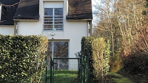 A two-story house with a dark roof, a white facade, and a small window with a shutter. - House (53m2) for vacations by the sea (La Forêt-Fouesnant)