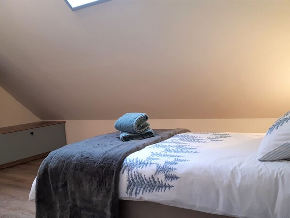 A bedroom with a bed, a rolled-up towel, and a window.