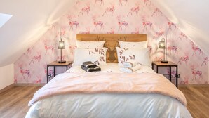 A cozy bedroom with a sloped ceiling, a wooden headboard, and a floral wallpaper design. - Charming Getaway with Garden, WiFi, and Garage in Scenic Gouy-les-Groseillers (Gouy-les-Groseillers)
