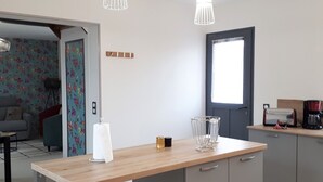 A modern kitchen with a wooden countertop, two pendant lights, a coffee maker, and a door leading to another room. - Charming Getaway with Garden, WiFi, and Garage in Scenic Gouy-les-Groseillers (Gouy-les-Groseillers)