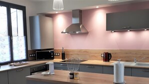 A modern kitchen with a central island, a built-in oven, a microwave, and a kettle. - Charming Getaway with Garden, WiFi, and Garage in Scenic Gouy-les-Groseillers (Gouy-les-Groseillers)