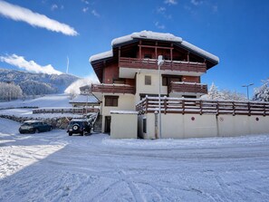 Ein zweistöckiges Gebäude mit einem hölzernen Balkon, einer Steinwand und einem mit Schnee bedeckten Dach.