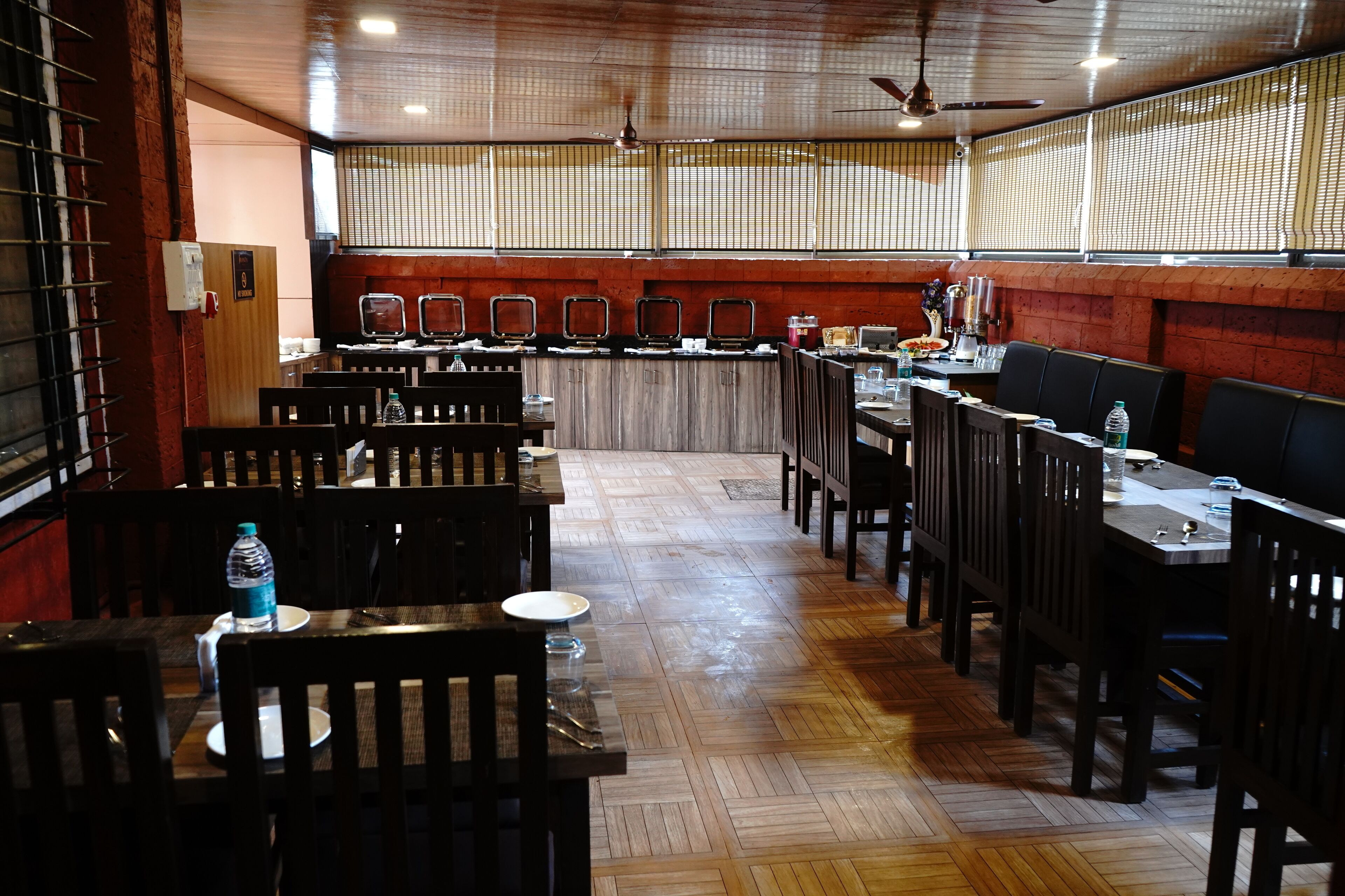 A restaurant with wooden flooring, multiple tables and chairs, and a counter with various items.