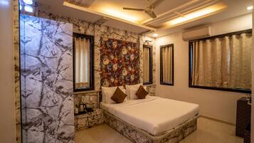 A bedroom with a marble-patterned wall, a floral mural, a bed with white bedding, and a ceiling fan.