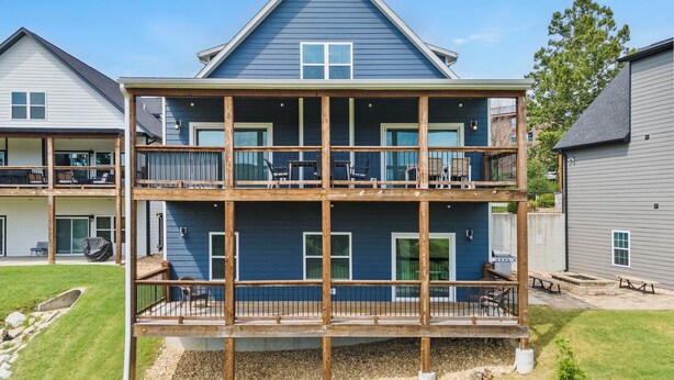 A two-story building with a balcony on the upper floor, a covered outdoor seating area, and a small garden. - Luxury 7BR Reunion Lodge on Thousand Hills Golf Course | Sleeps 22 | Near Highway 76 (Branson)