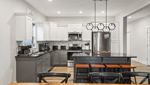 Una cocina moderna con armarios blancos, electrodomésticos de acero inoxidable y una isla central con taburetes de bar.