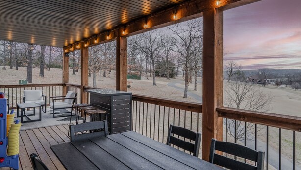 Una terraza techada al aire libre con mobiliario de madera, una mesa y sillas.