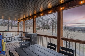 Eine überdachte Terrasse im Freien mit Holzmöbeln, einem Tisch und Stühlen.