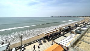 Un paseo marítimo frente a la playa con un café y zona de estar con vistas al océano.