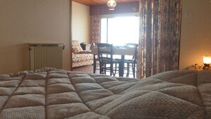 Una habitación acogedora con una cama grande, una mesa de comedor con sillas y vistas al exterior por una ventana.