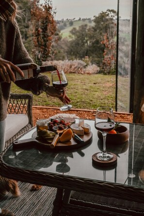Une table dressée avec du fromage, des fruits et des verres à vin, et une personne qui verse du vin.