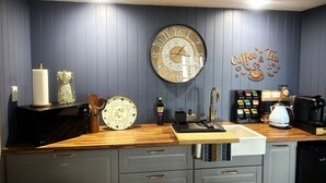 Una cocina con encimera de madera, un lavabo, una cafetera y un reloj en la pared.
