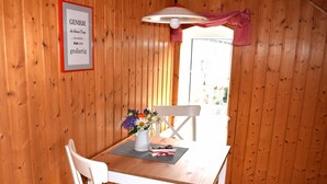 A wooden interior with a white table, a chair, a vase with flowers, and a sign on the wall. - Ferienwohnung Andresen - FW Andresen (Pommerby)