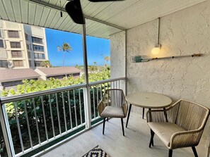 Enjoy the serene view from this balcony with a pair of wicker chairs and a small table.
