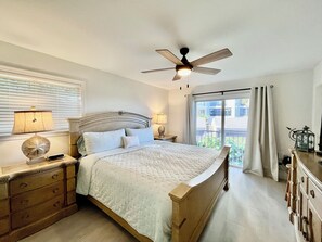 Cozy retreat with a large bed, ceiling fan, and balcony views.