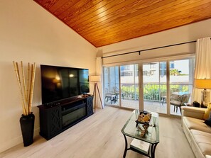 Relax in this stylish living room with a flat-screen TV, glass coffee table, and sliding door leading to a balcony with a view.