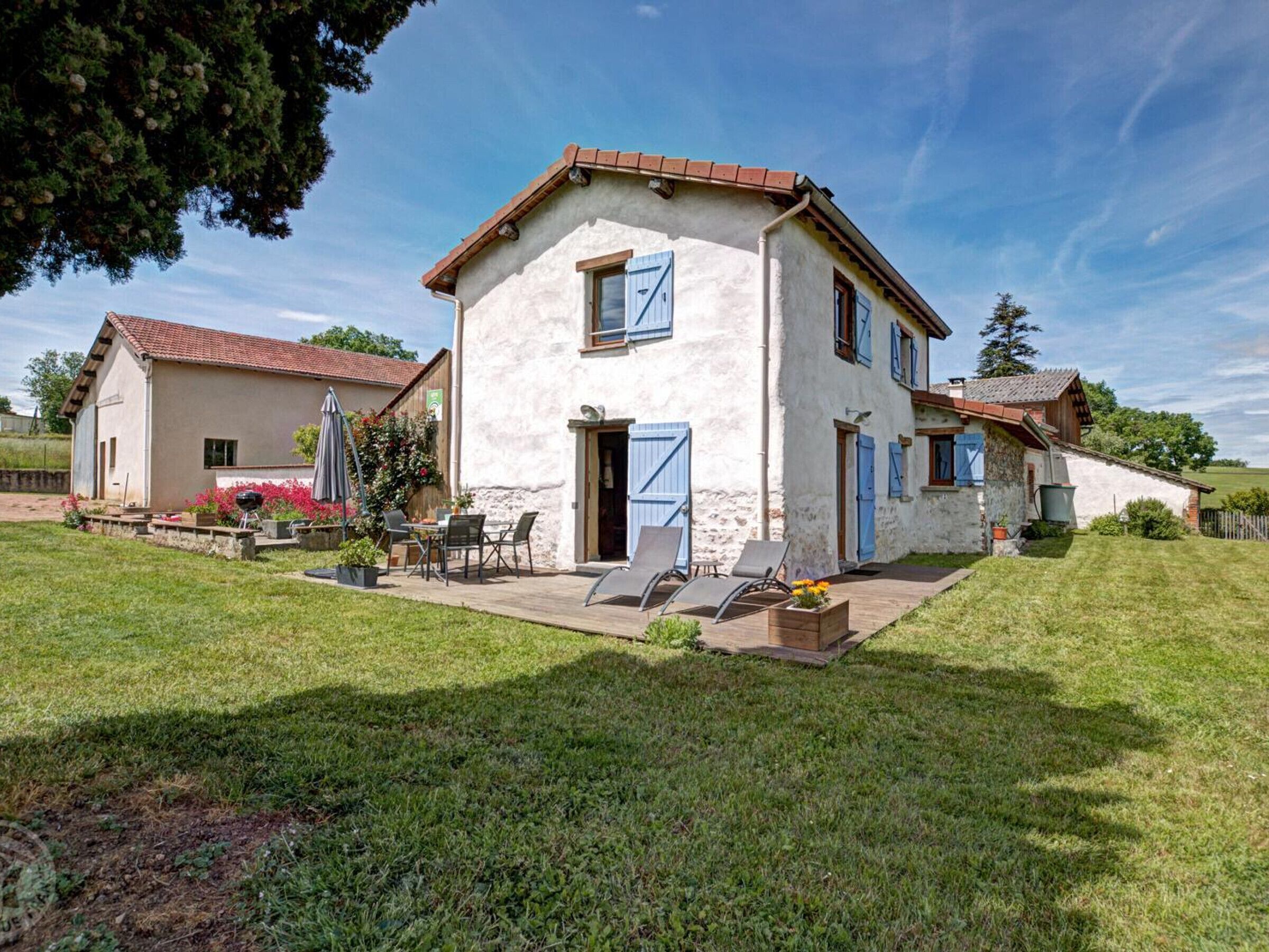 A two-story house with a patio, a barbecue area, and a small garden.