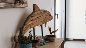 Una escultura de madera de un pez sobre una mesa con plantas en macetas y un cactus.