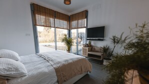 Un dormitorio con cama, televisor y vistas al exterior.