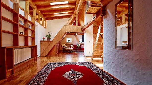 Un vaste loft doté de hauts plafonds, de poutres apparentes et d’un escalier central.