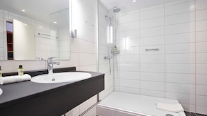 Une salle de bain moderne avec un lavabo blanc, un miroir et une douche.