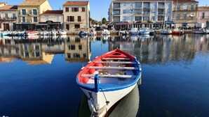 Een jachthaven met aangemeerde boten, kalm water en gebouwen op de achtergrond.