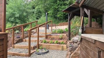A wooden deck with steps leading to a garden area, surrounded by trees.