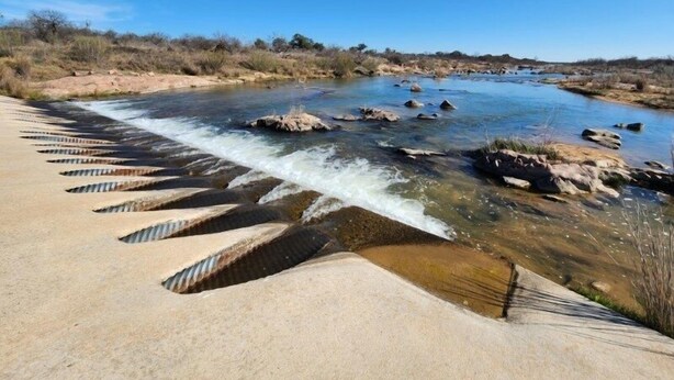 Une rivière bordée d’une digue en béton et d’une série de marches descendant vers l’eau.