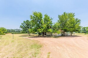 Escape to a serene rural retreat surrounded by mature trees and a well-manicured lawn.