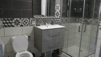 Un baño con inodoro, lavamanos y ducha.