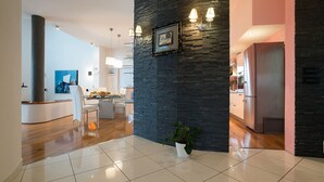 A modern kitchen with a black stone accent wall, stainless steel appliances, and a dining area with a white table and chairs. - Villa Aylin, 5-bed, Next to the sea (Medulin)