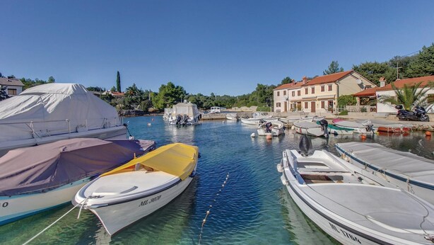 Un port de plaisance avec plusieurs bateaux amarrés, une zone abritée et des bâtiments en arrière-plan.