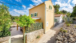 Une maison de plain-pied avec un mur en pierre et un petit jardin.