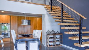 A modern kitchen with a dining table, chairs, and a hanging light fixture. - The Clubhouse - On Golf Course - Serene Retreat (Searcy)