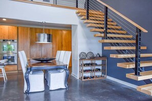 Une cuisine moderne avec une table à manger, des chaises et un luminaire suspendu.