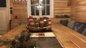 A cozy cabin interior with a wooden bench, a central table with candles, pine decorations, and a window with a snowflake decoration. - Das Alte Forsthaus Spiegelhütte Wohnung Wildbach (Lindberg)