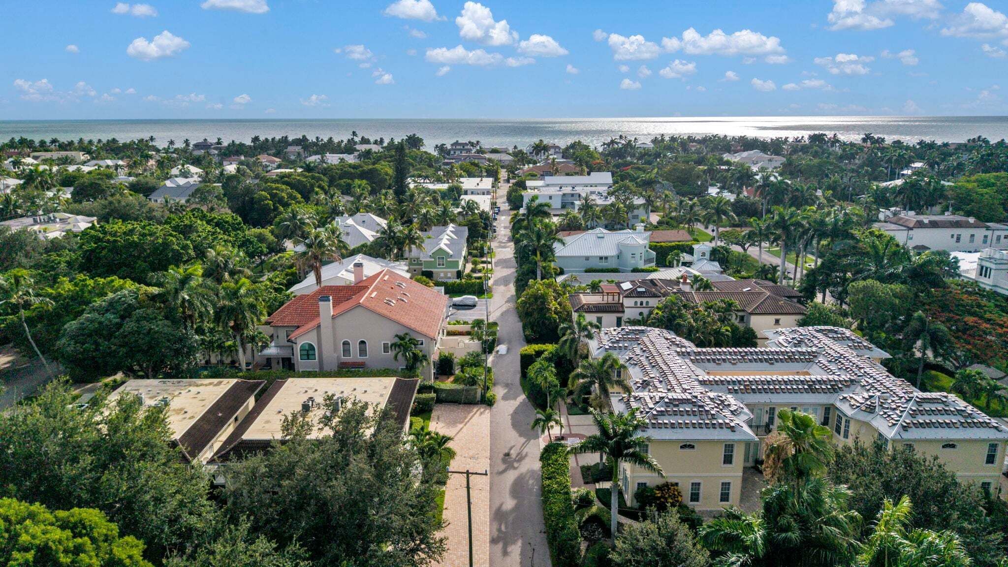 A coastal residential area with houses, a clear sky, and a view of the ocean.