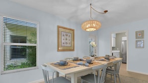 A dining area with a long table, chairs, and a hanging light fixture.