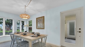 A dining area with a table set for four, a hanging light fixture, and a door with a window.